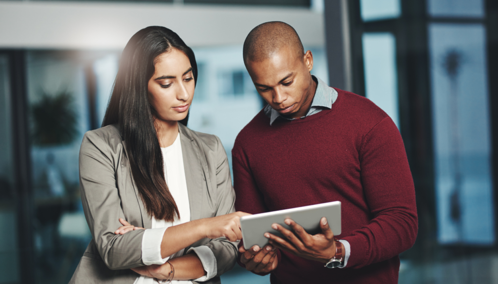 Dois profissionais analisando informações em um tablet, simbolizando colaboração e tomada de decisões estratégicas em um ambiente corporativo.