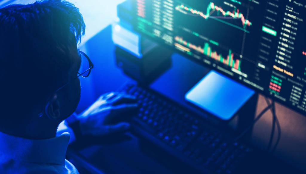 Domine a Análise de Mercado Financeiro Homem analisando gráficos de investimento em uma tela de computador, representando operações financeiras e análise de mercado.