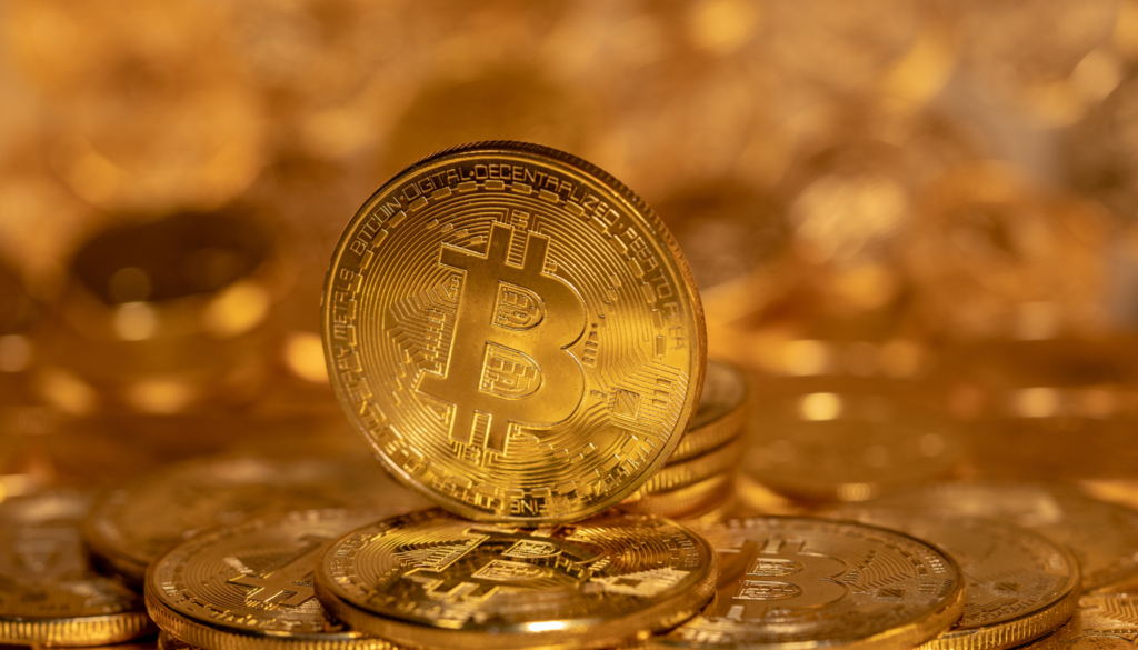 Bitcoin: A criptomoeda que lidera o mercado global. Moeda dourada de Bitcoin em destaque, com outras moedas desfocadas ao fundo, representando o valor e a popularidade das criptomoedas no mercado financeiro.